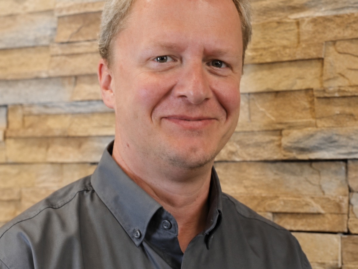 Portrait of Stephan Sommer wearing a gray Food Science shirt in front of a stacked-stone wall.